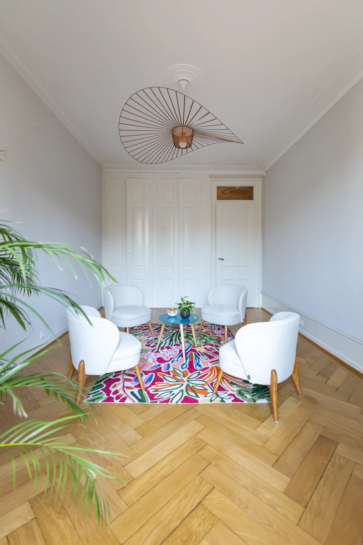 Salle lumineuse de Maison Sama à Genève, fauteuils clairs et parquet en point de Hongrie